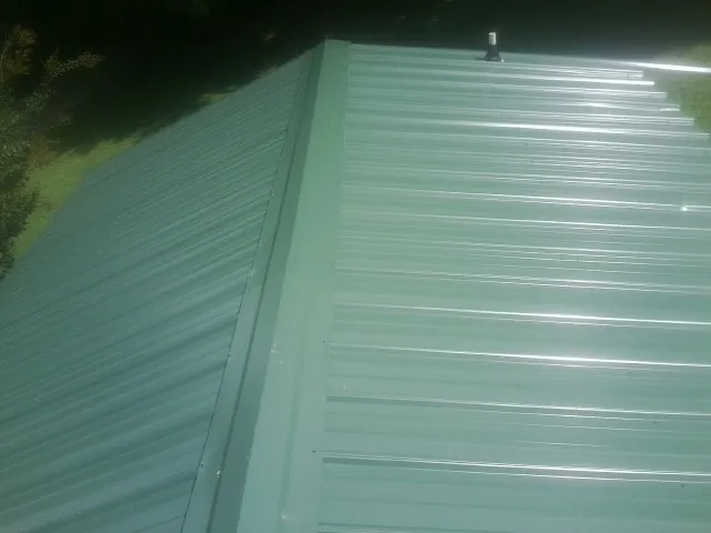 New green metal panels meeting at the ridge of a roof — Flat Roof Repair work by our crew in Goodyear