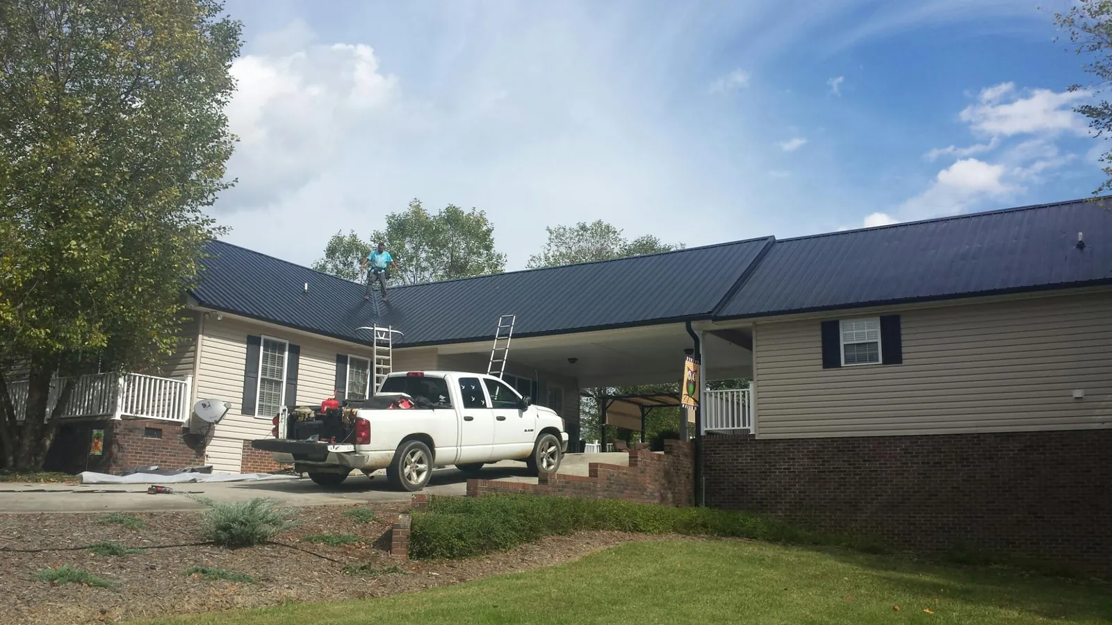 Black metal roof over a home and attached breezeway with ladders set in Goodyear