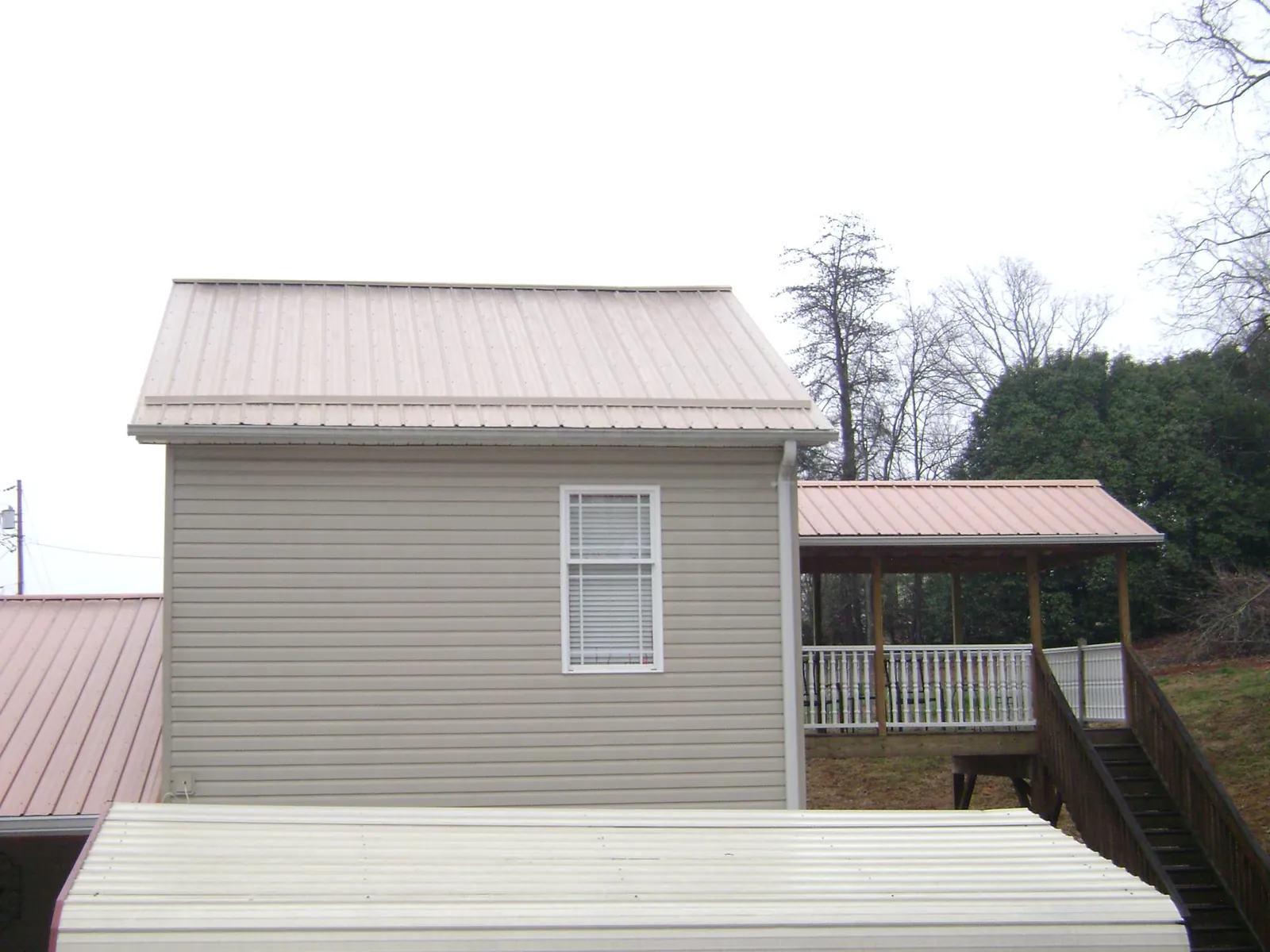 Tan metal roofs on a two story addition and attached porch, from a Roof Replacement job in Goodyear