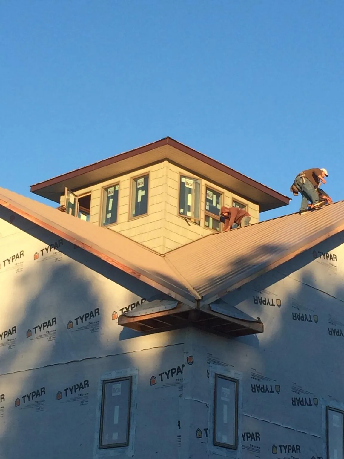 Roofers working around a rooftop cupola on a new metal roof at sunset — Roof Waterproofing in Goodyear by Roofing Brothers